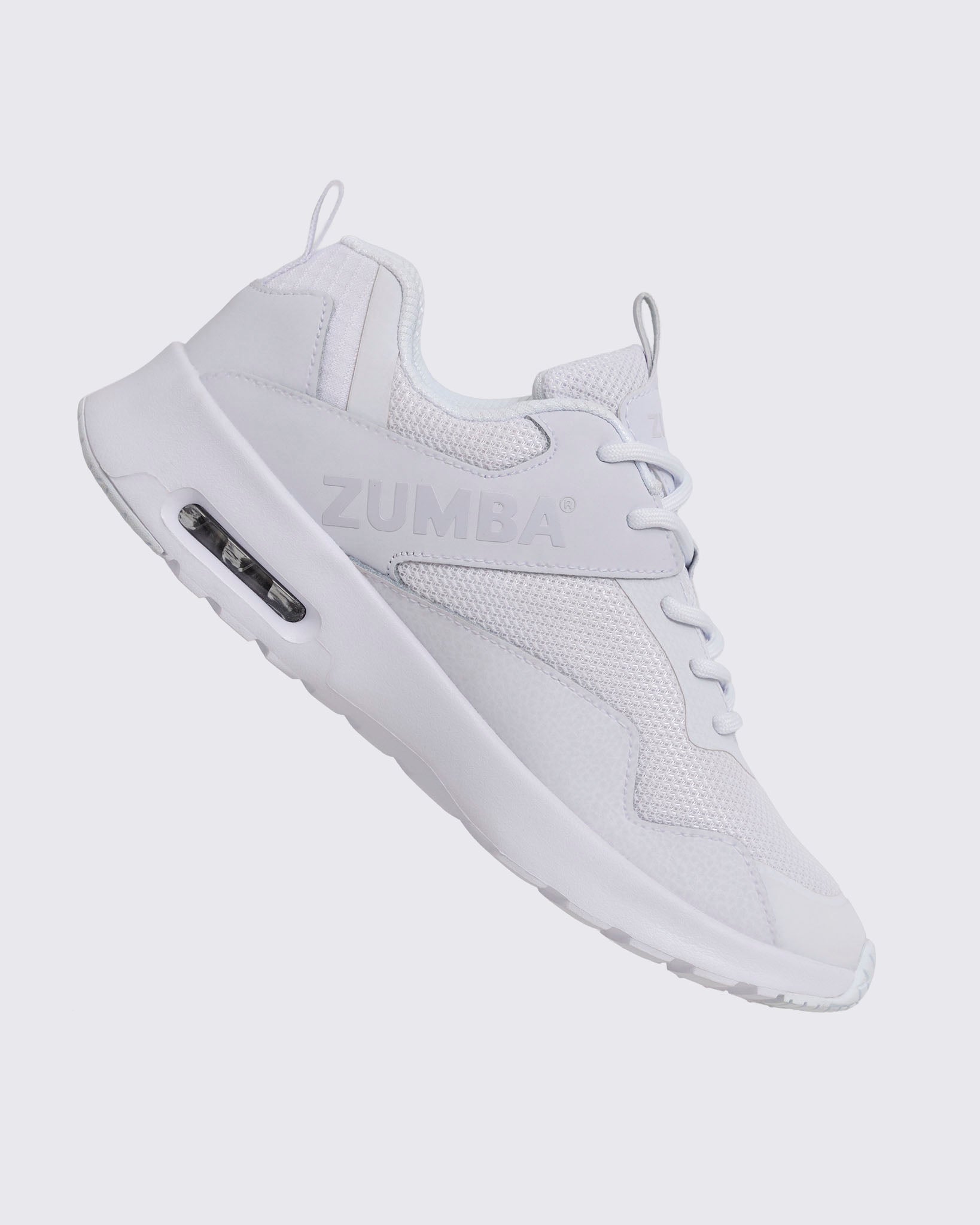 White Zumba low-top athletic sneaker shown from the opposite side, with textured mesh panels, white laces, embossed side logo, and thick white sole with a visible air unit.