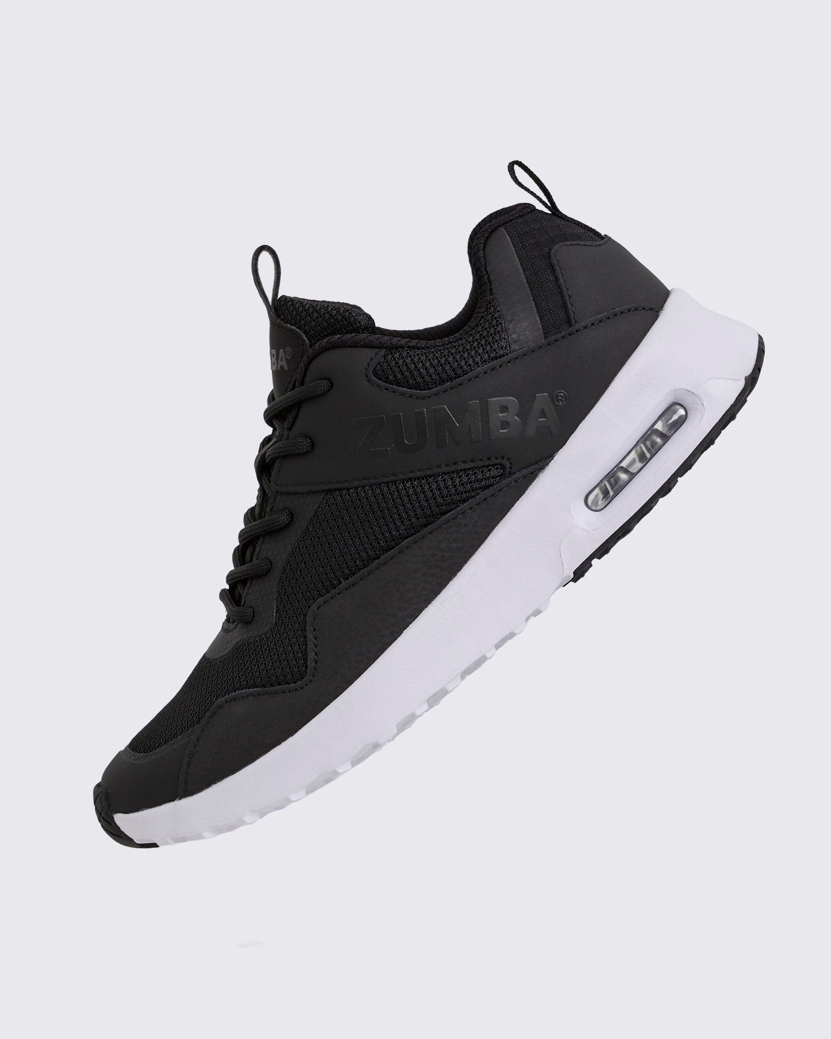 Black Zumba low-top athletic sneaker shown in a side angle, featuring a breathable mesh upper, tonal lace-up closure, embossed Zumba logo, and chunky white sole with visible air cushioning.