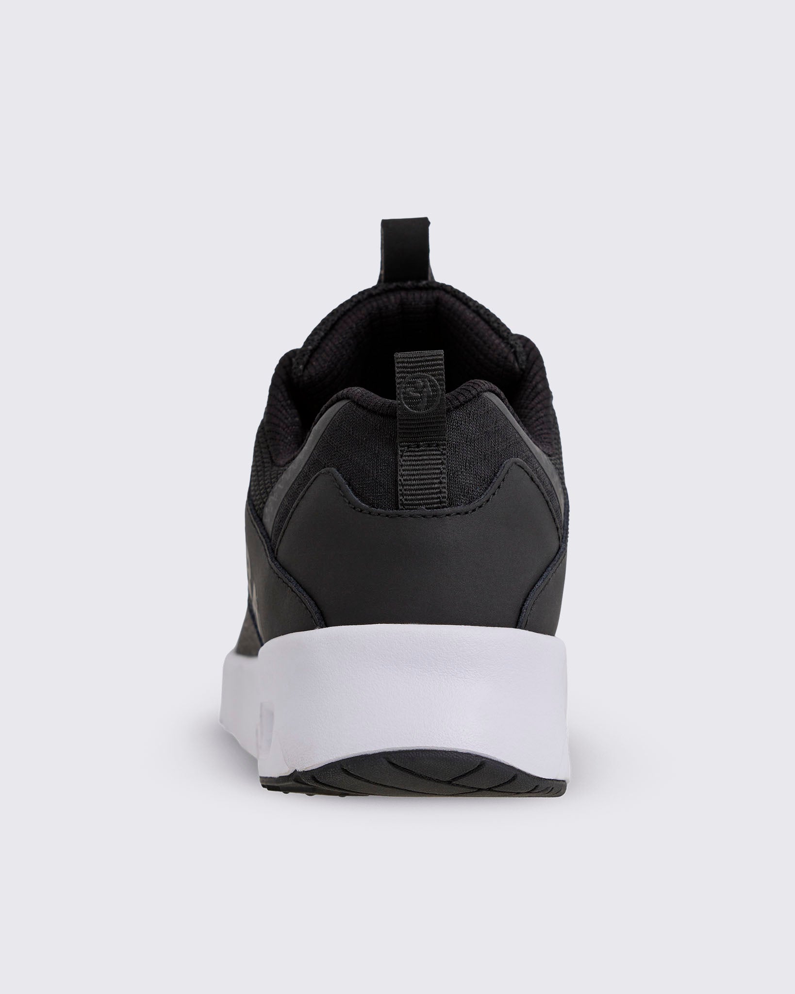 Black Zumba low-top athletic sneaker shown from the back, with a padded collar, heel pull tab, smooth heel overlay, and thick white sole with black tread.