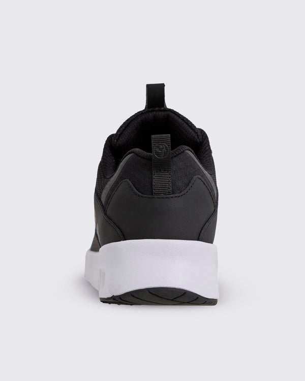 Black Zumba low-top athletic sneaker shown from the back, with a padded collar, heel pull tab, smooth heel overlay, and thick white sole with black tread.