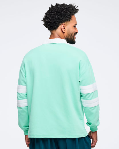 Back view of a mint green rugby sweatshirt with white collar and double white sleeve stripes on a male model, photographed on a white background.
