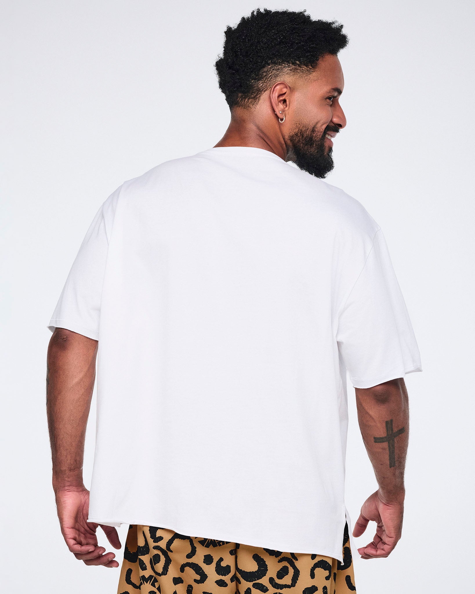 White oversized T-shirt, shown from the back on a smiling male model wearing tan leopard-print cargo pants.