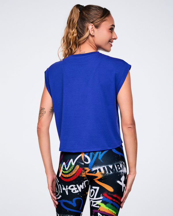 Female model wearing a blue sleeveless top, shown from the back, paired with colorful leggings on a white background.