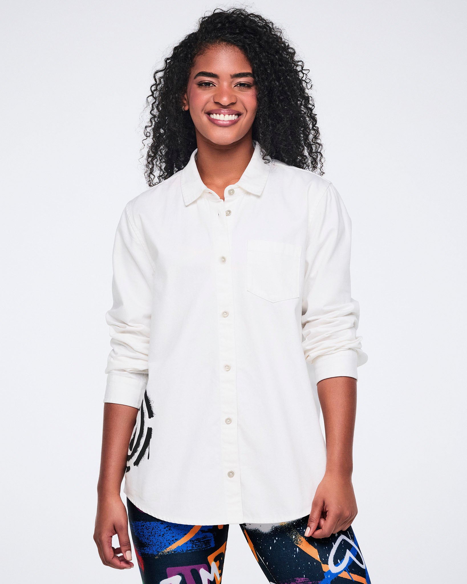 Female model wearing a white button-down shirt and colorful leggings on a white background.