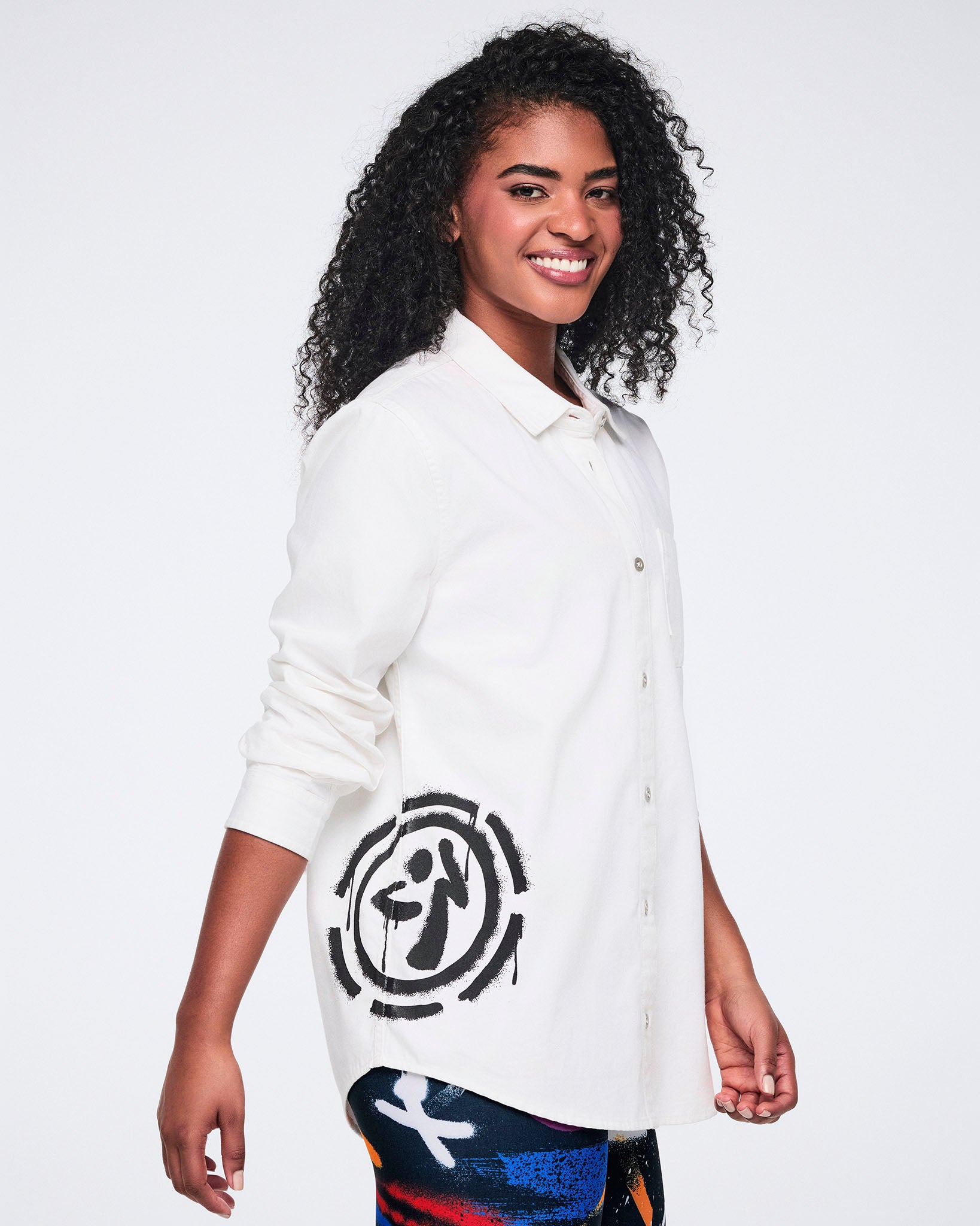 Female model wearing a white button down with a black 'Zumbito' on a white background.