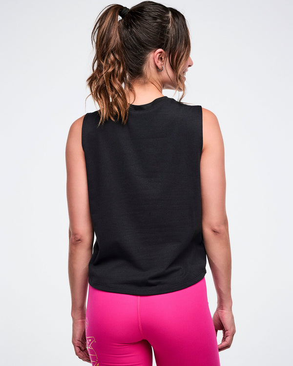 Back view of a female model wearing a black sleeveless Zumba top and pink shorts on a white background.
