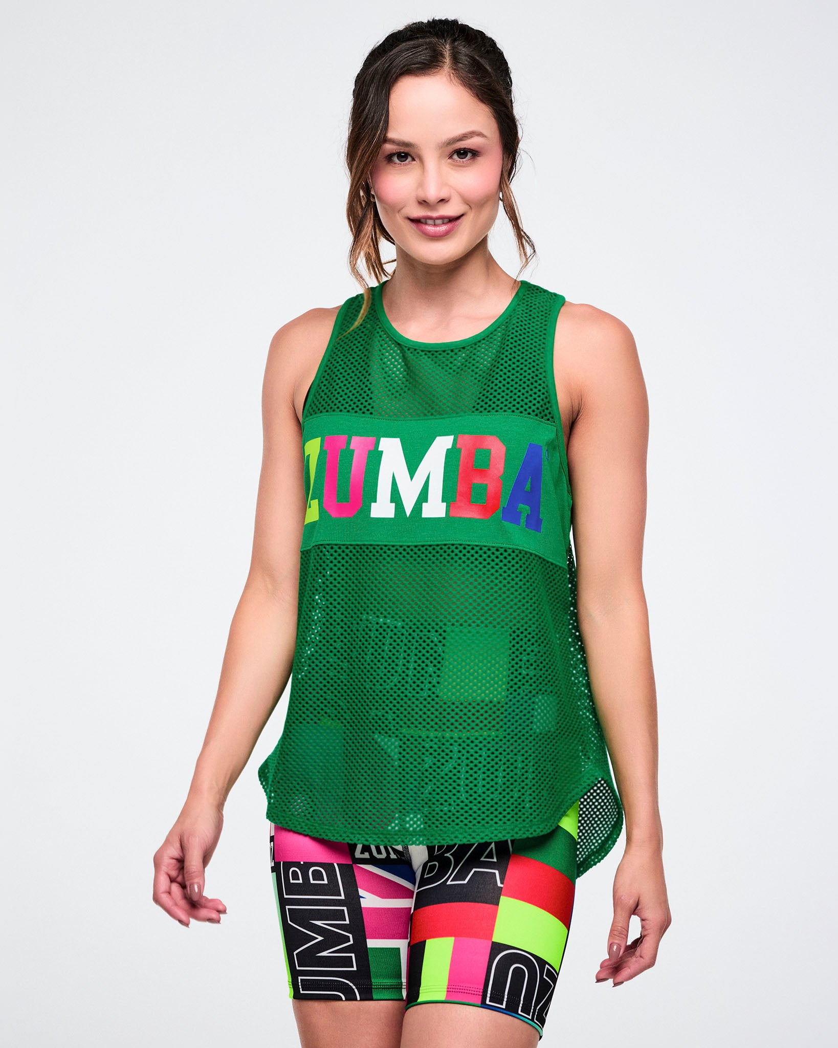 Female model wearing a green mesh tank with colorful 'Zumba' branding on a white background.