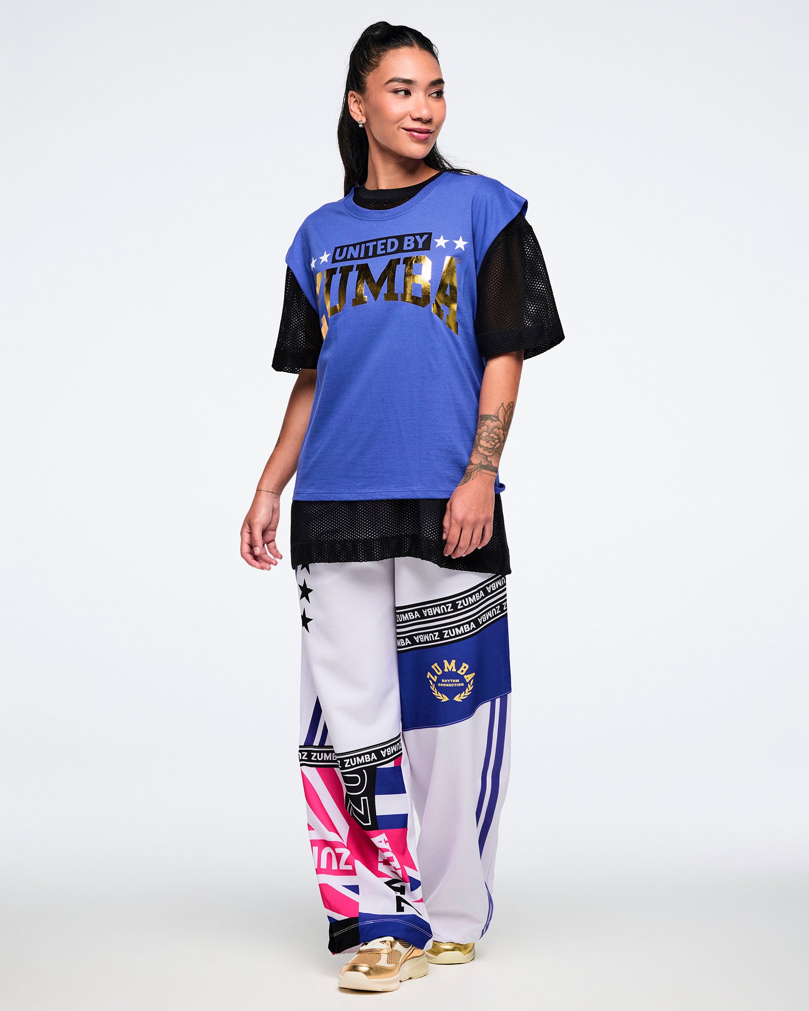 Female model wearing a blue and black outfit with 'Zumba' branding on a white background.