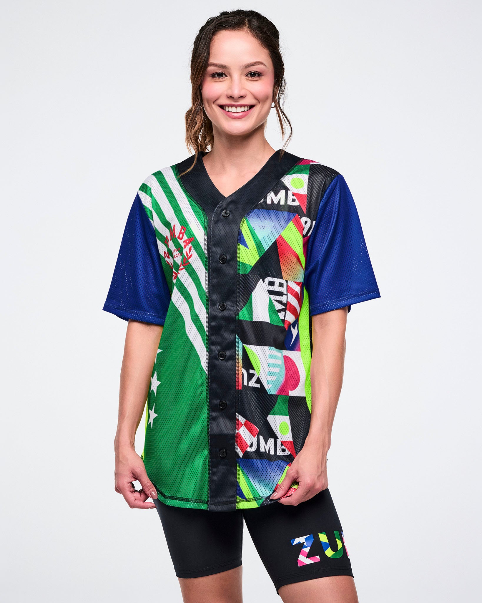 Female model wearing a colorful sports jersey with various patterns on a white background.