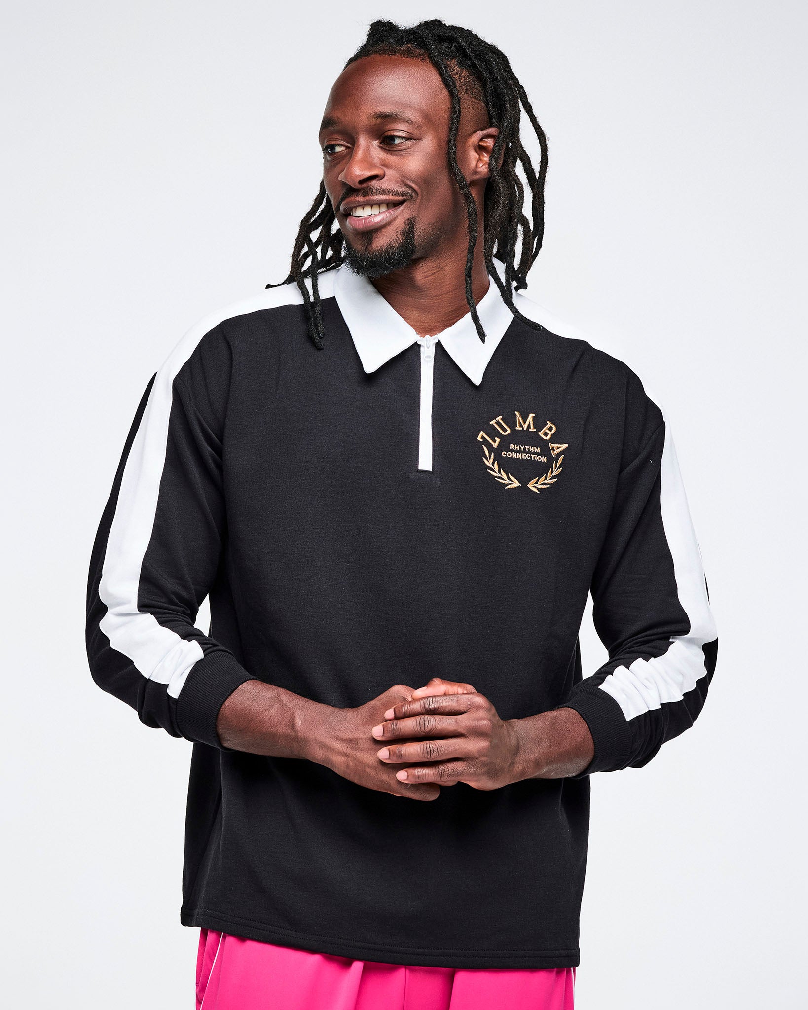 Male model in black-and-white polo with a gold Zumba logo “Rhythm Connection” on the upper left, on a white background.