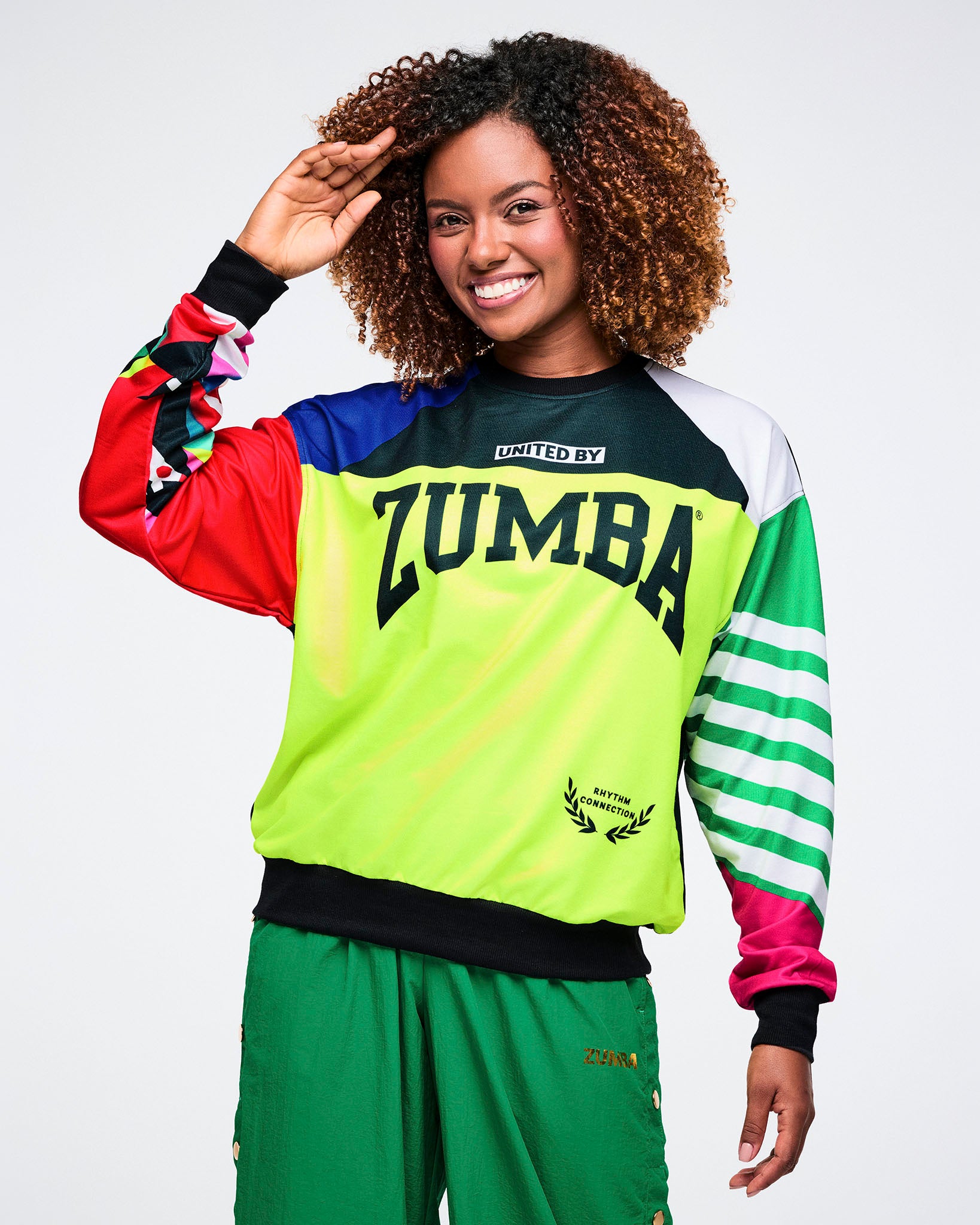 Female model wearing a colorful Zumba shirt on a white background.