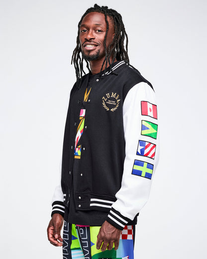 Side view of a male model wearing a black varsity jacket with colorful flag designs on a white background.