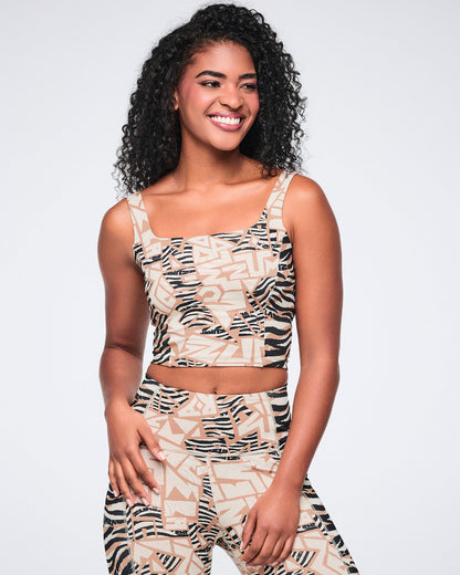 Female model wearing a matching set with a beige, cream, and black abstract zebra-print cropped tank featuring a square neckline and wide straps, paired with matching high-waisted leggings.