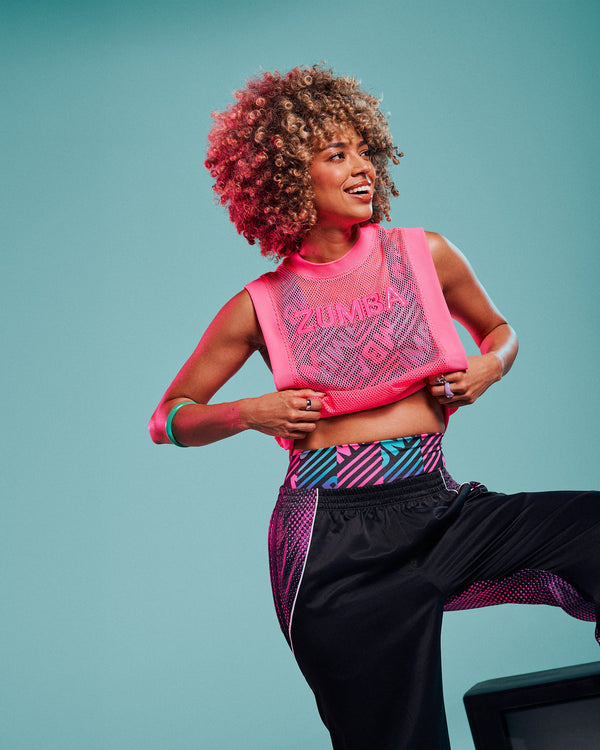 Female model wearing a pink mesh tank with embroidered 