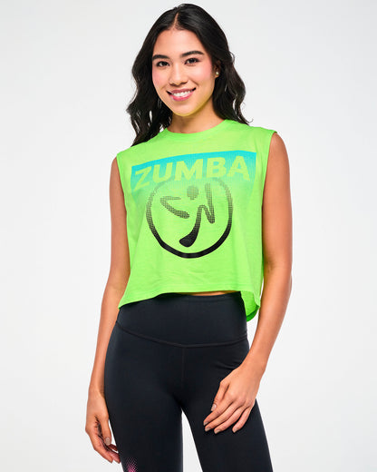 Female model wearing a neon green tank with white "ZUMBA" text on a aqua patch and a black dot pattern Zumbito logo, paired with black leggings.