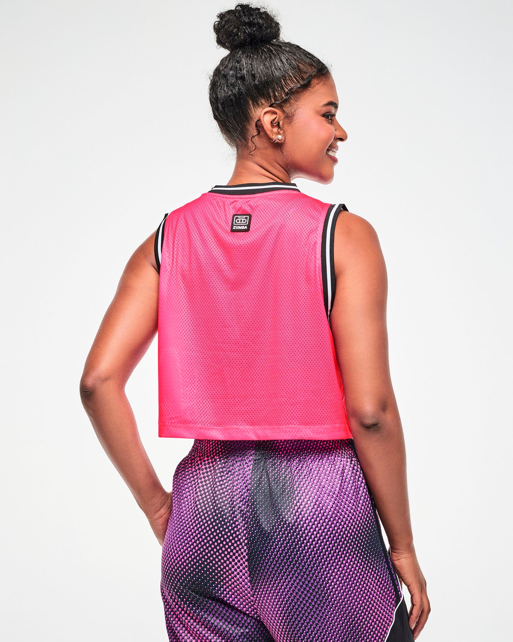 Shown from the back, female model wearing a pink mesh tank, with the cassette tape tag toward the top and pink and black dot pants.