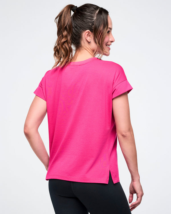 Female model from the back, wearing a bright pink t-shirt on a white background.