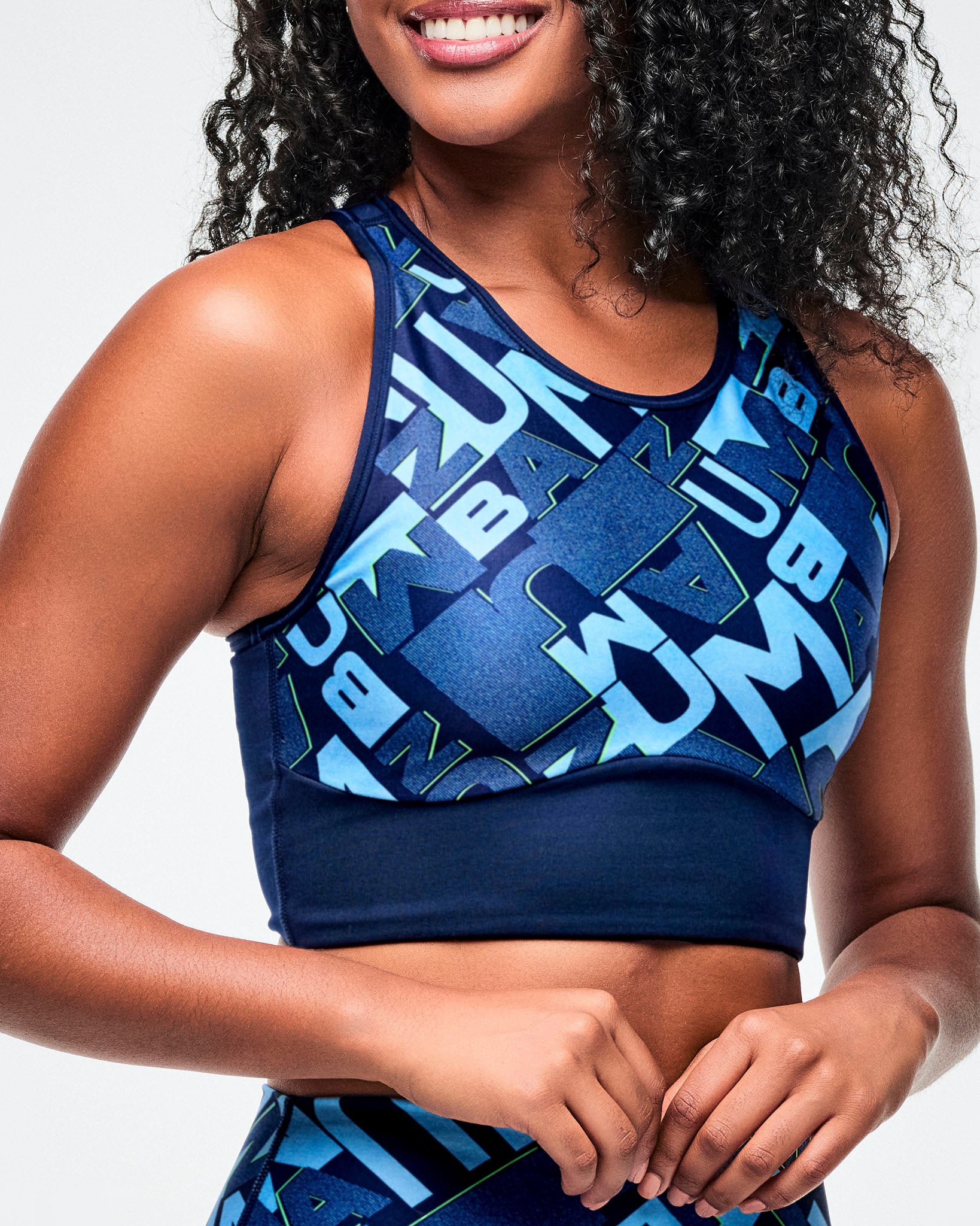 Close-up of female model wearing a blue sports bra with geometric pattern on a plain background.