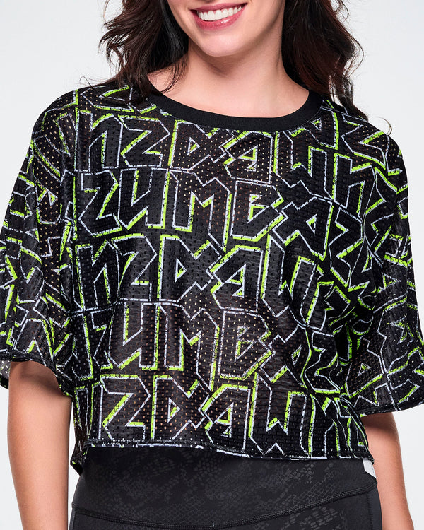 Close-up view of a female model wearing a short-sleeve mesh boxy crop top with rock-like letter patterning that says 