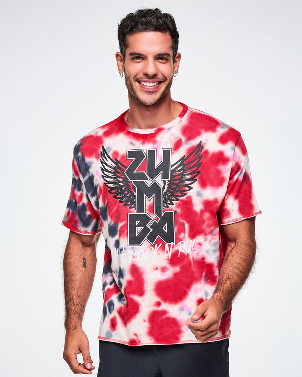 A male model wearing an oversized red, white, and black tie-dye patterned tee with a large black winged 'ZUMBA' rock / metal like logo and white 'LOVE+ROCK N' ROLL,