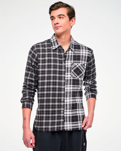 A male model wearing a long-sleeve button-up plaid shirt with a black, white, and gray checkered pattern, paired with black pants.