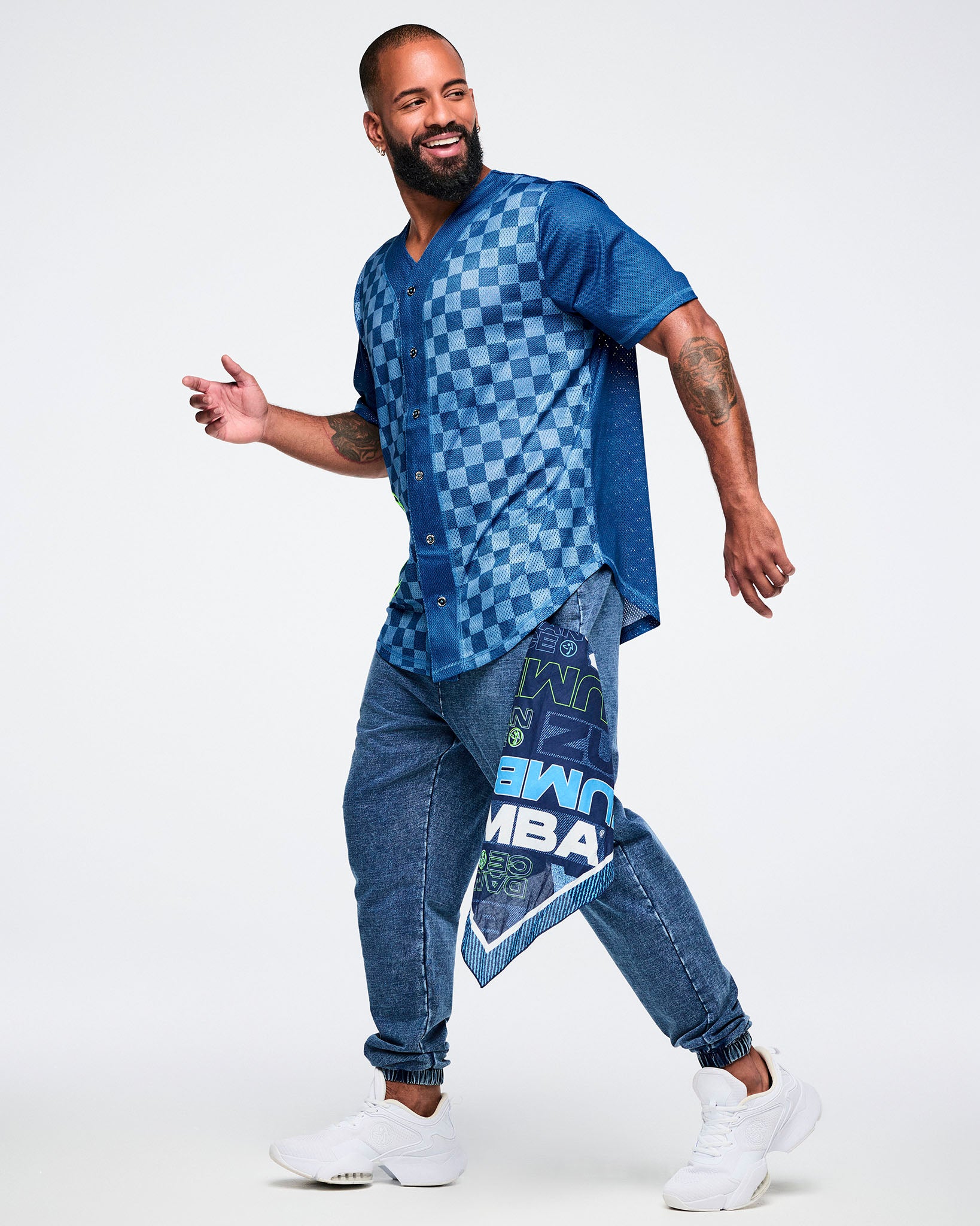 Male model wearing a blue checkered button-up jersey with matching blue jeans and a blue Zumba bandana hanging from the pocket.