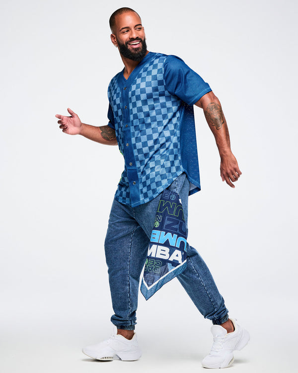 Male model wearing a blue checkered button-up jersey with matching blue jeans and a blue Zumba bandana hanging from the pocket.