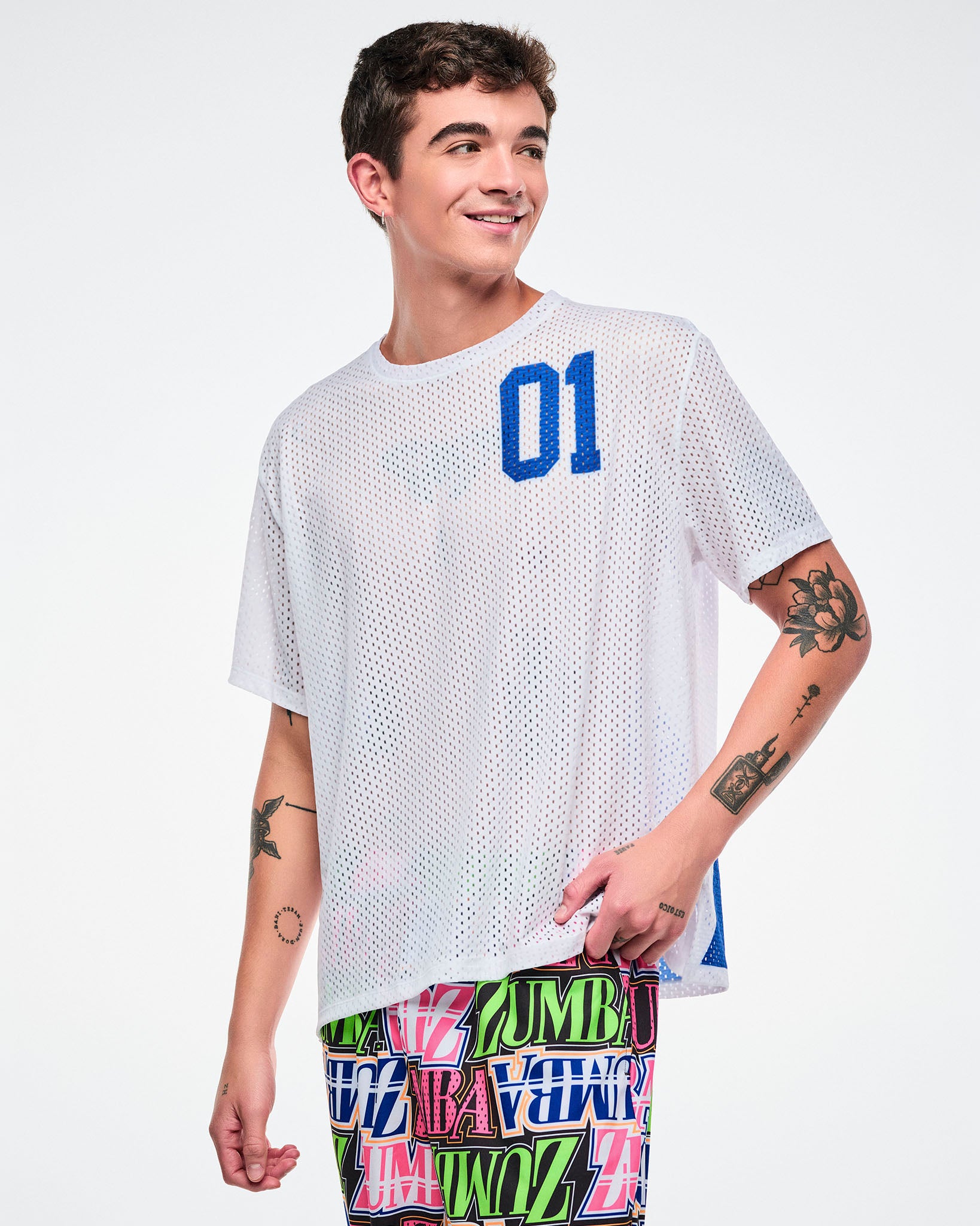 Male model wearing a white mesh top with a blue number '01' and colorful pants on a white background.