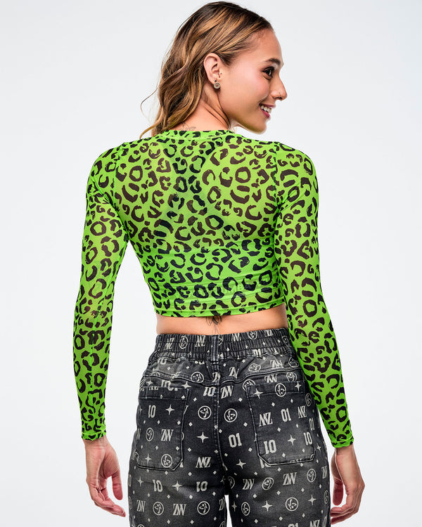 Back view of a female model wearing a green leopard print mesh crop top and black patterned denim jorts on a white background.