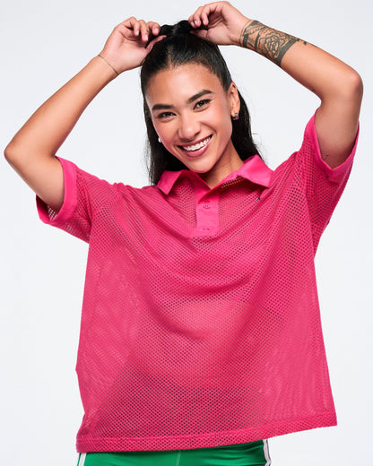 Close view of the pink mesh polo with female model posing with her arms over her head against a white background.