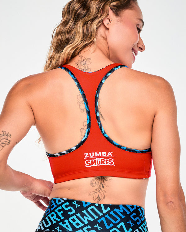 Back view of the red side of the bra, showing the racerback and white 'ZUMBA' over 'THE SMURFS' logos below the shoulder blades.