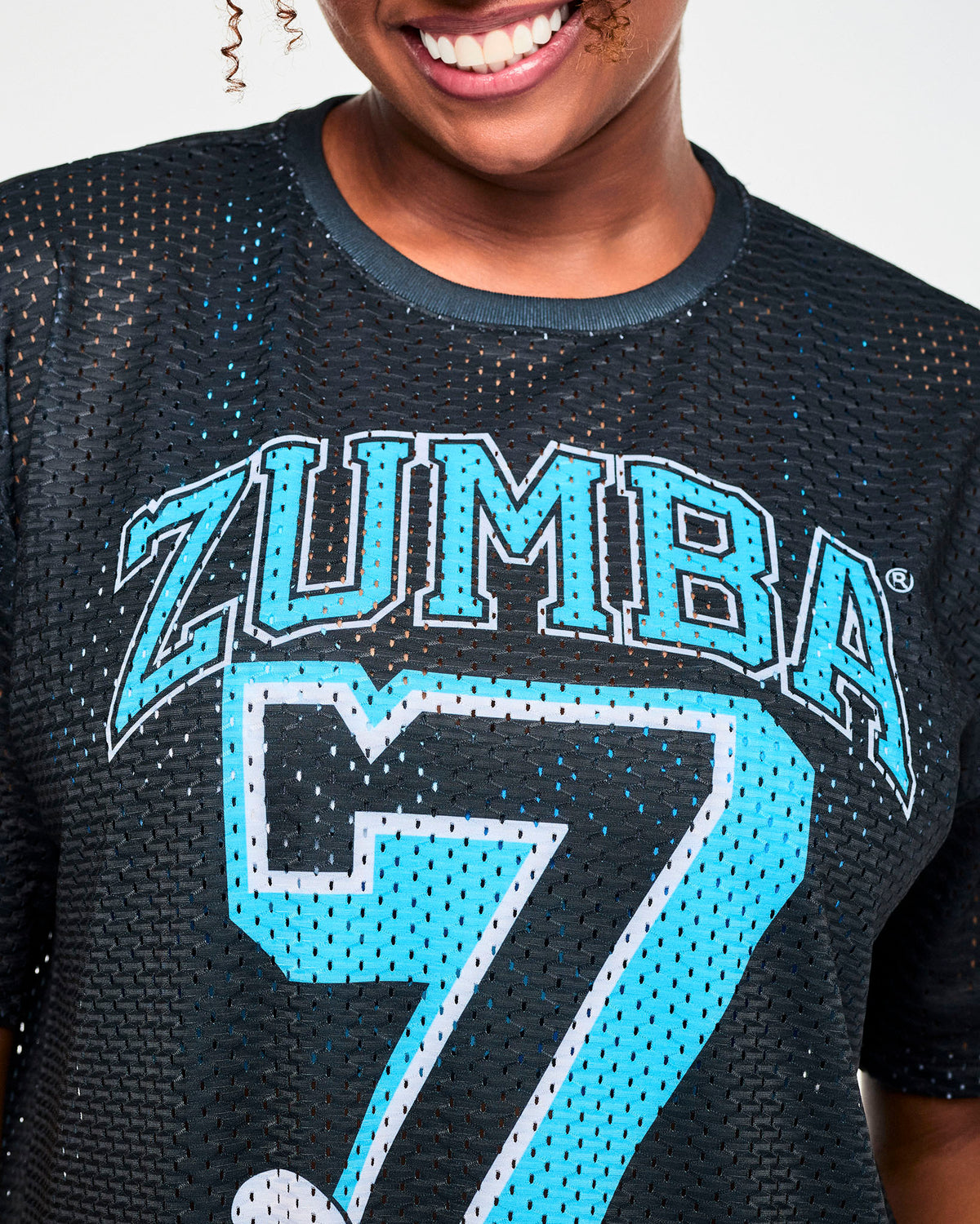 Close-up of the mesh top's front, showing the open-hole texture through the light blue 'ZUMBA' lettering and varsity 'Z.'