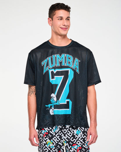 Male model in the black mesh boxy tee with the arched 'ZUMBA' text, varsity 'Z,' and leaning Smurf graphic. Paired with Smurfs print cargo pants.