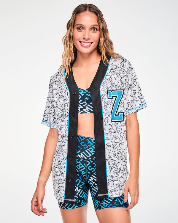 Female model wearing the Smurfs line-art baseball jersey unbuttoned and open over a matching blue and black 'ZUMBA' X 'THE SMURFS' print bra and biker shorts.