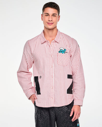 Male model in the red and white striped long-sleeve button-up, with the embroidered Smurf peeking from the diagonal-striped left chest pocket and large black 'ZUMBA' letters wrapping around the hem. Paired with black tonal logo print bottoms.