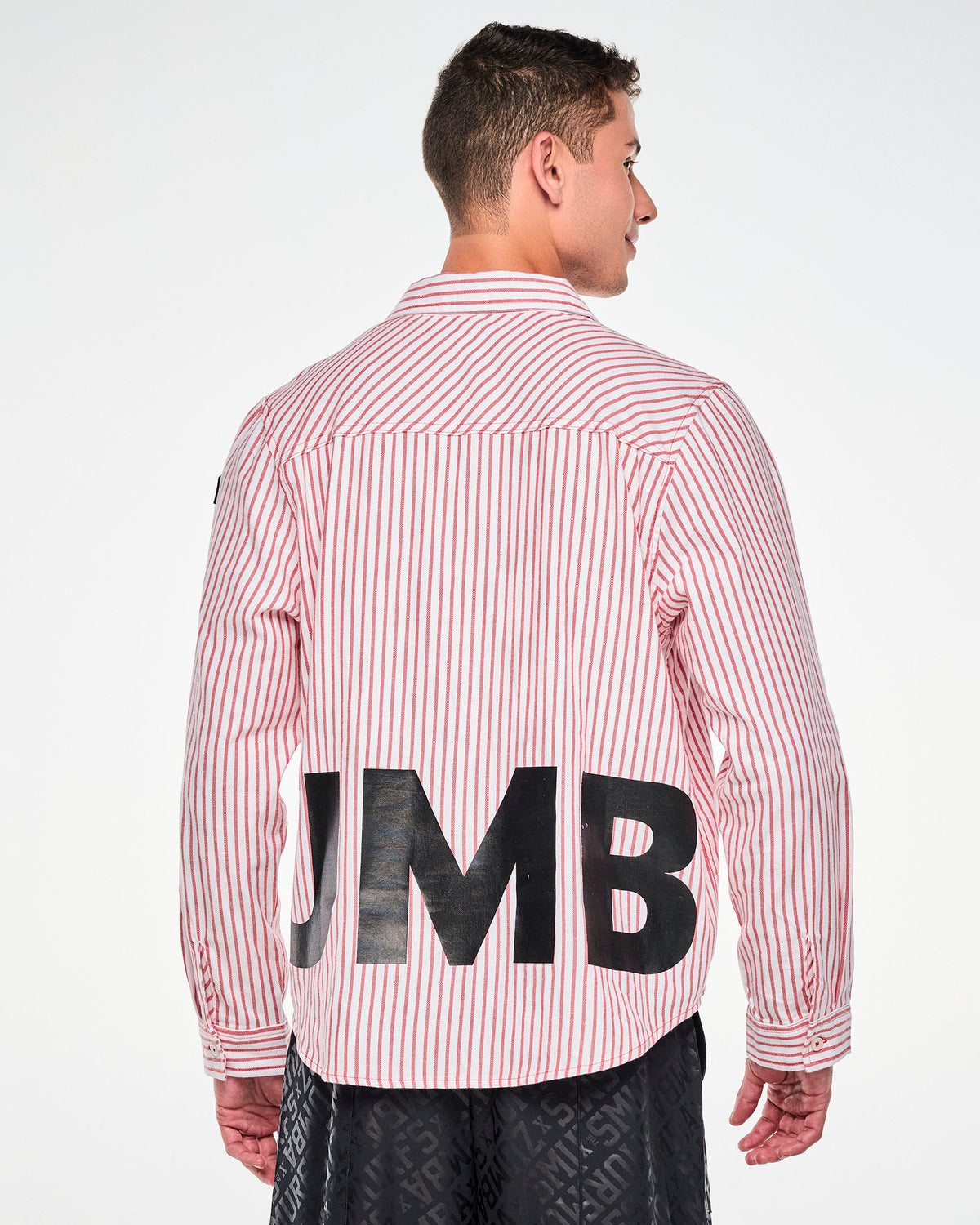 Back view of a male model in the red and white striped shirt, showing part of the black 'ZUMBA' lettering across the lower back and the buttoned cuffs.