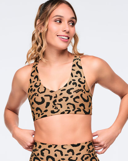 Leopard-print sports bra with black abstract spots and a scoop neckline, shown on a female model in a matching leopard-print biker shorts set.