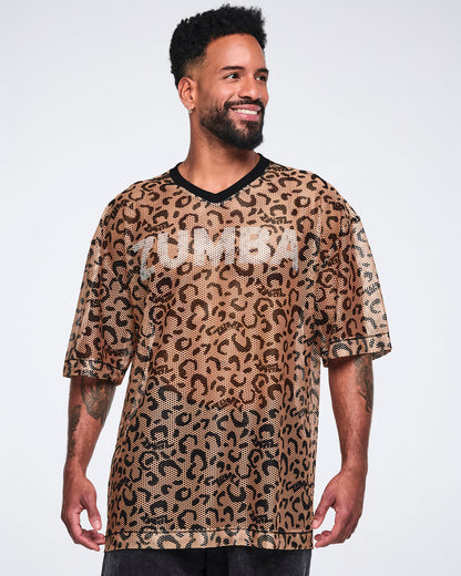 Tan leopard-print mesh top with black abstract spots, a black V-neck collar, oversized fit, and elbow-length sleeves, shown on a smiling male model wearing black long shorts.