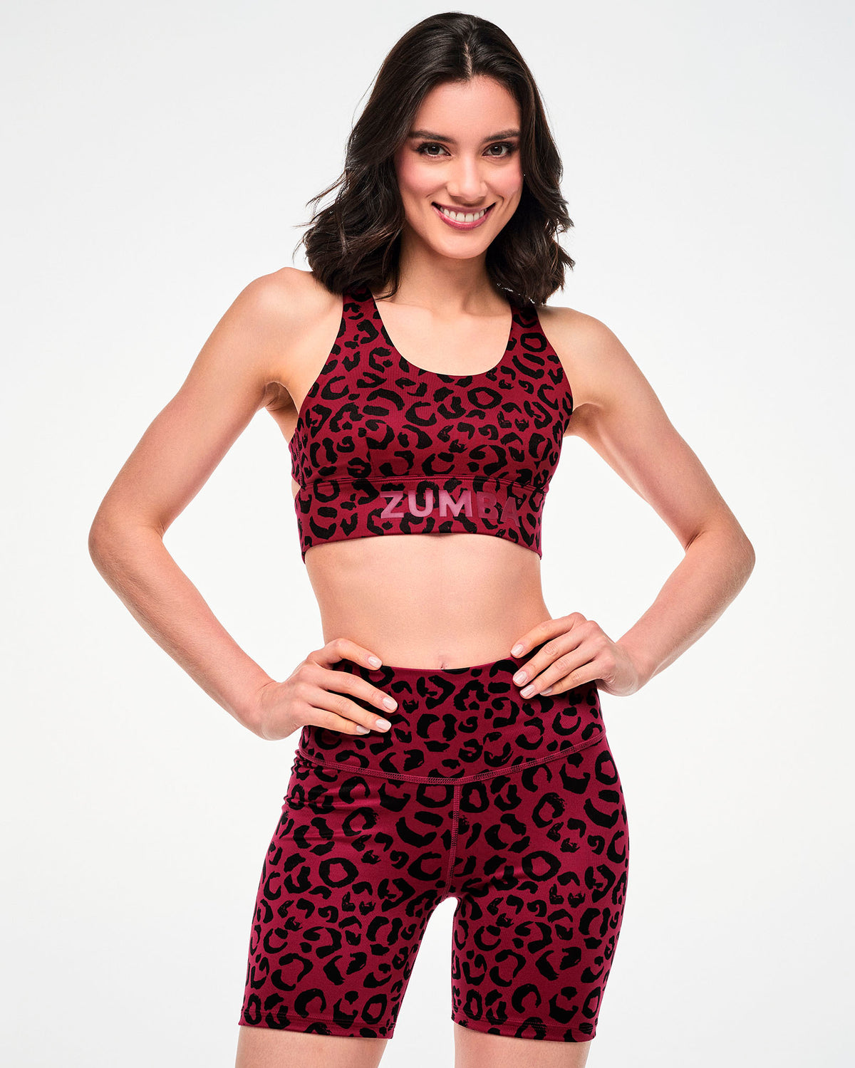 Female model with hands on her hips in the dark red leopard print longline bra and matching high-waisted biker shorts.