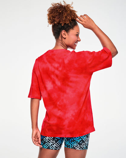 Back view of a female model in a red and light cloud fabric wash Smurfs graphic tee, showing a plain back and a relaxed, long fit.