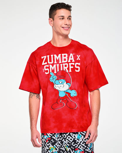 Male model in the oversized red and light cloud fabric wash tee with the white 'ZUMBA' X 'THE SMURFS' text and pointing Papa Smurf graphic. Paired with black and white Smurfs character print bottoms.