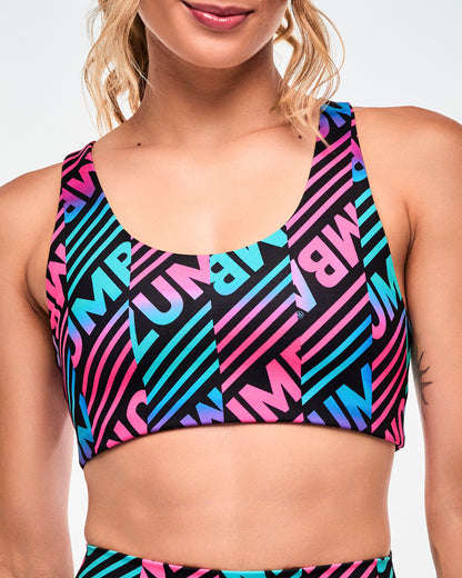 Close-up of a reversible sports bra with a pink, aqua, and black diagonal "ZUMBA" stripe print.