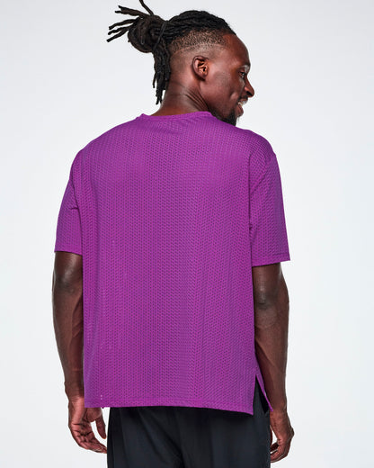 Back view of a male model in a purple oversized mesh boxy top, paired with black pants.