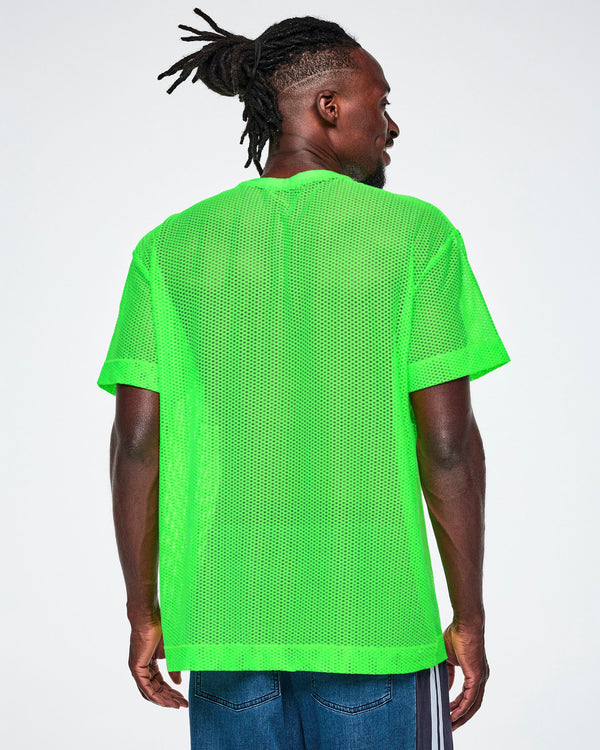 Back view of a male model wearing a bright green Zumba mesh top, paired with blue denim pants.