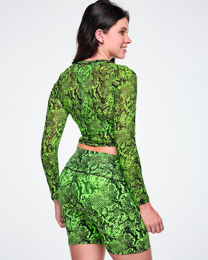 Back view of a female model wearing a matching green and black snakeskin print activewear set, featuring a long-sleeve mesh crop top and high-waisted biker shorts, against white background.