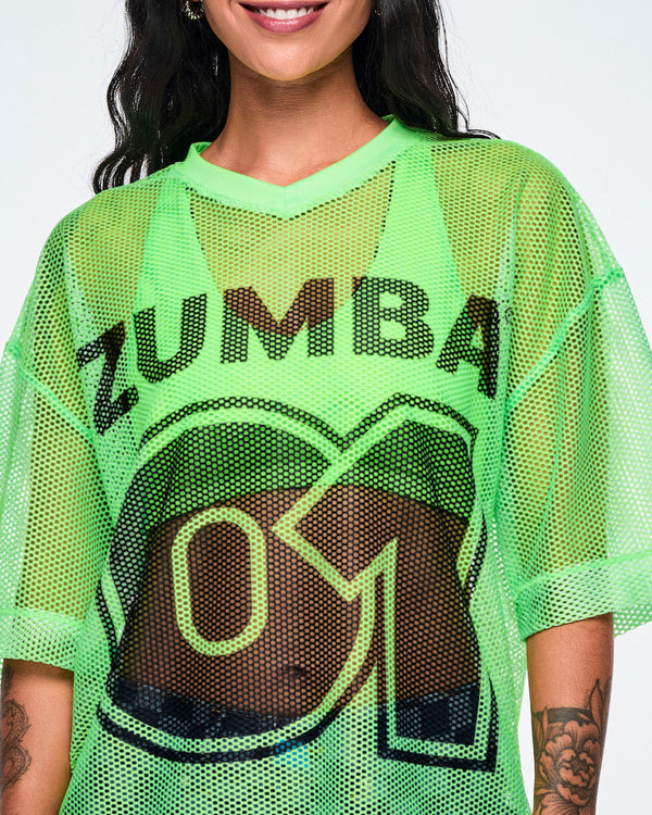 Close-up detail of a female model wearing a green mesh Zumba top, with a large black 
