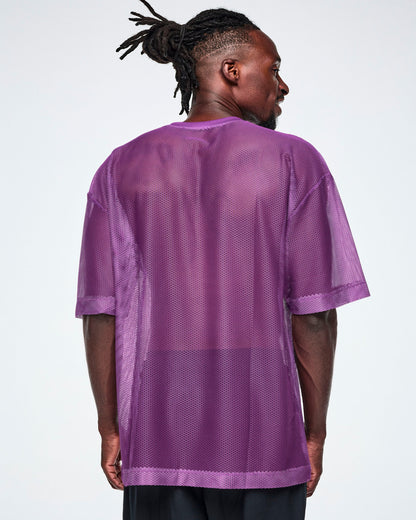 Back view of a male model wearing a purple mesh Zumba top, paired with black pants.