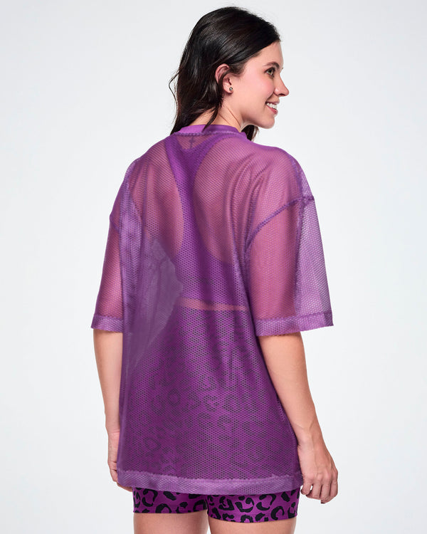 Back view of a female model wearing a purple mesh Zumba top, paired with purple leopard print high-waisted biker shorts.