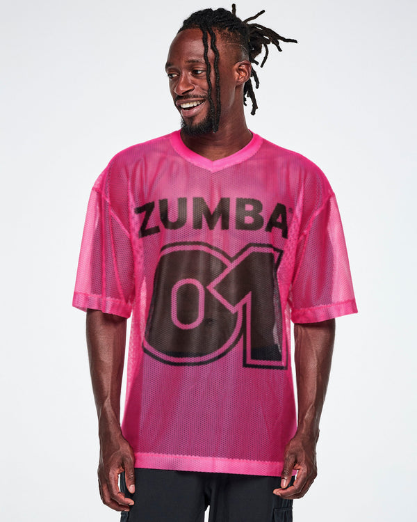 A male model wearing a pink mesh Zumba top with a large black 
