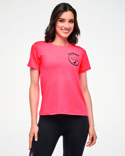 Female model wearing a pink tee with a black Zumbito logo, paired with black leggings, front view close-up.